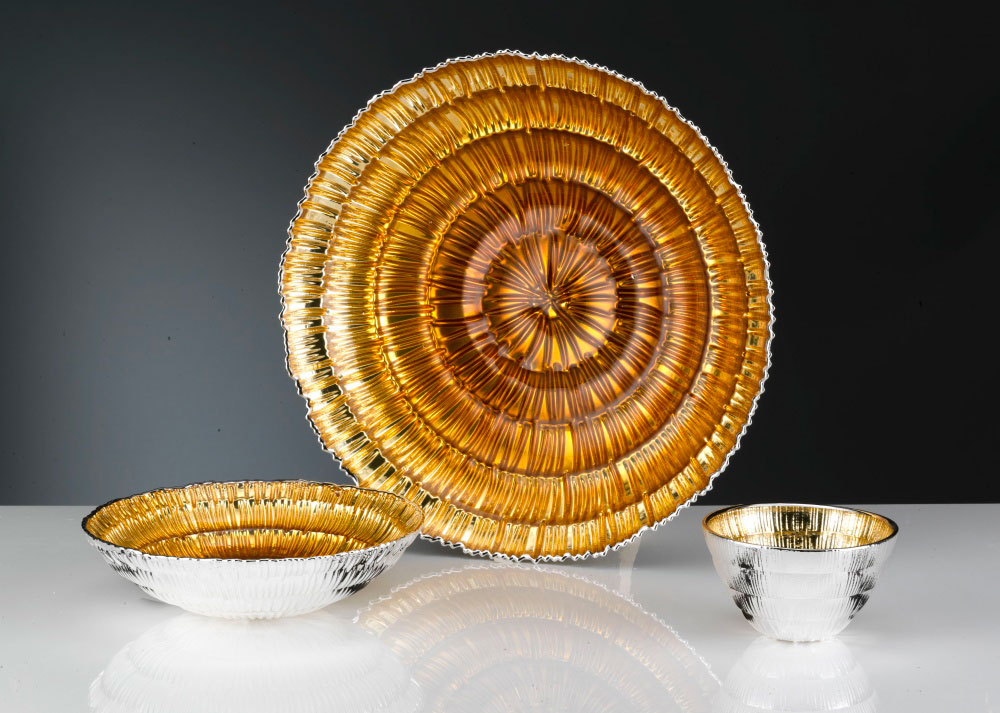 Set di piatti e ciotole di paglia intrecciata, tonalità dorate su sfondo scuro, stile artigianale rustico, primo piano.