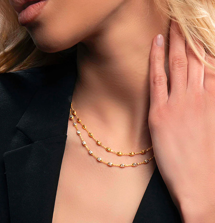 Doppia collana a catenina in oro giallo e bianco con elementi ovali intrecciati indossata da una modella