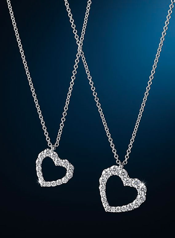 Collane in oro bianco con ciondolo a cuore in pav&eacute; di diamanti Recarlo esposte su sfondo blu