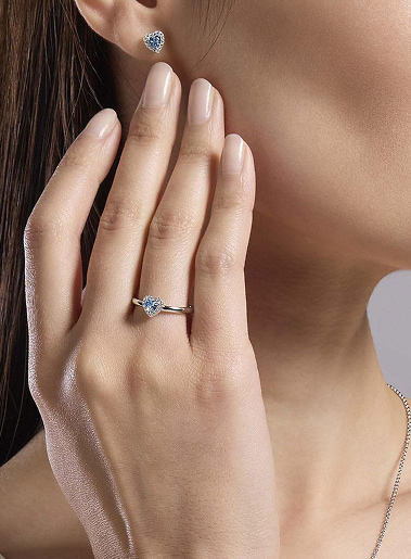 Anello solitario con pietra azzurra incastonata su dita femminili, primo piano elegante.
