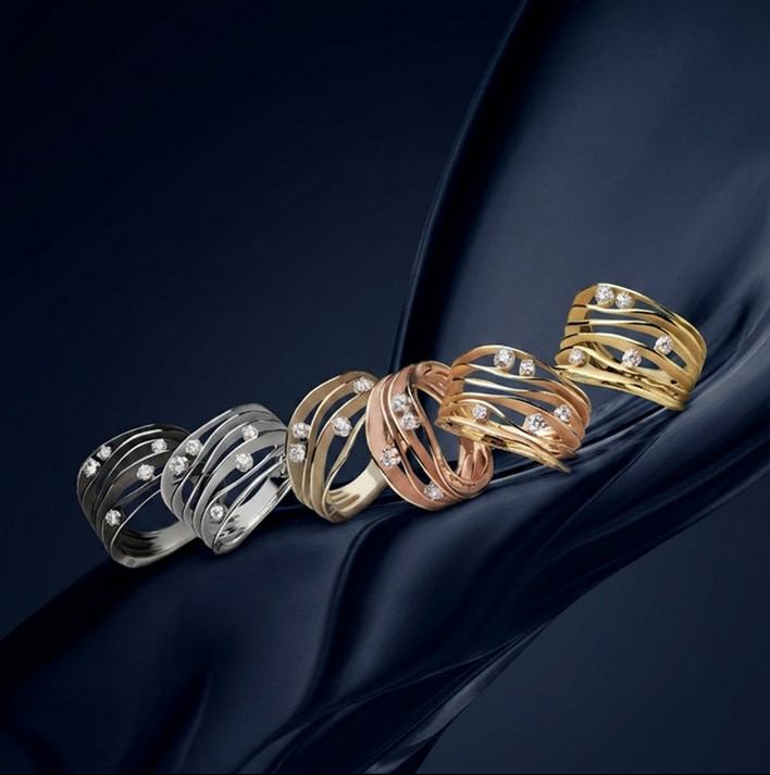 Collane intrecciate di anelli d'oro, bianco e rosa con pietre brillanti su sfondo scuro, elegante e lucente.
