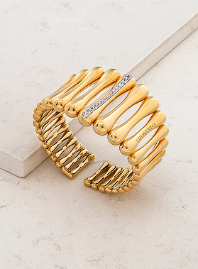 Bracciali rigidi dorati con anelli intrecciati e una file di pietre incastonate, elegante gioiello da polso.