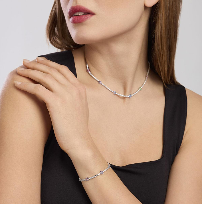 Donna indossa collana sottile argentata con perle lucenti, scatto ravvicinato del collo e spalle nudo.