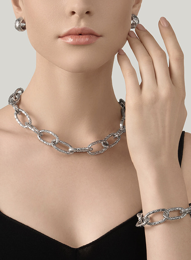 Collana pendente in argento a grandi anelli ovali indossata sul collo di una donna, primo piano minimalista e lucente.