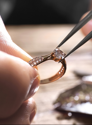 Anello con diamante finemente incastonato tra i tubi delle pinze, primo piano su una mano che lo tiene delicatamente.