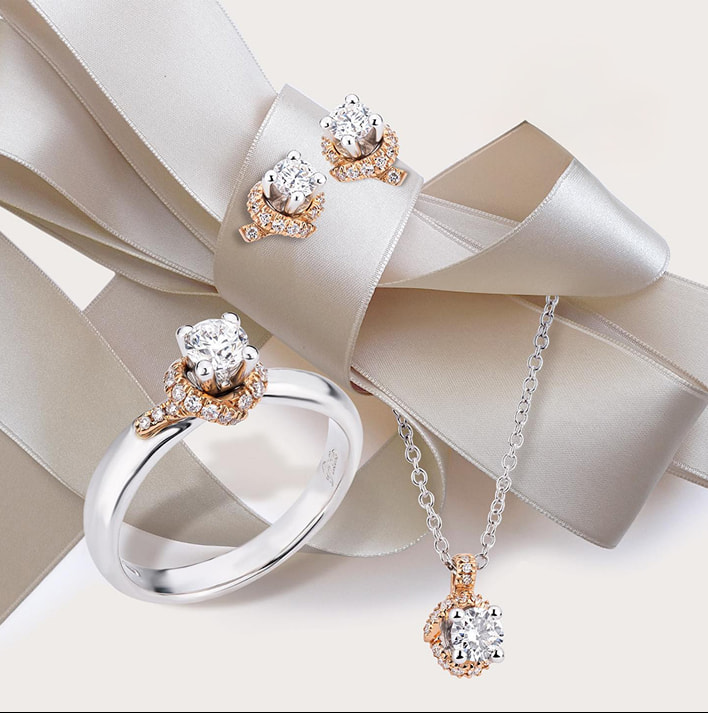 Collezione gioielli di matrimonio: anello solitario con zircone, orecchini dorati e collana su seta beige con nastro elegante.