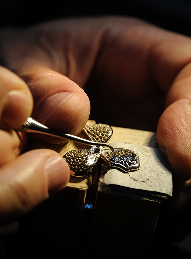 Ora in lavorazione: tornita una piccola fibbia o distintivo in metallo, mani esperte al lavoro con strumenti di precisione.