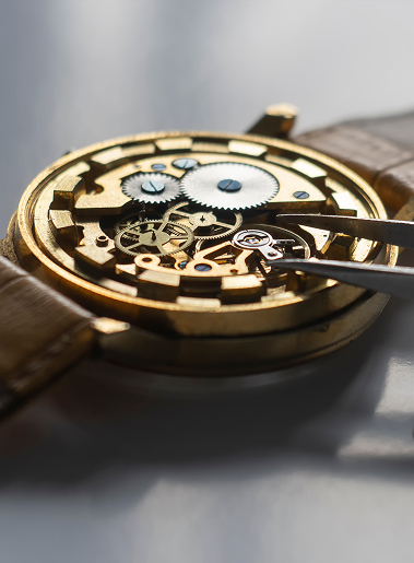 Interno di orologio antico: ingranaggi in ottone e ruote visibili, strumenti per regolazione e lancette mancano.