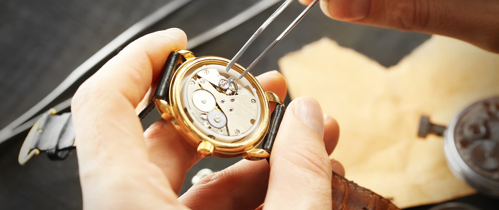 Riparazione orologio da polso: mani guidano strumenti sottili sul movimento interno del orologio d'oro.