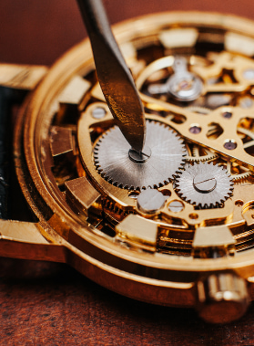 Dettagli d'orologio meccanico: ingranaggi dorati, ruote e viti, con una lama che gira una piccola vite al centro di un ingranaggio